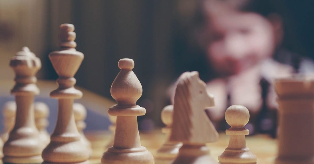Wooden chess pieces mid-game with a knight about to move